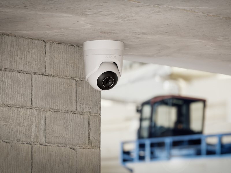 Caméra Ajax TurretCam blanche fixée au plafond d’un entrepôt